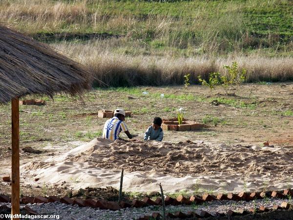 Madagassischer Vater und Sohn, die im Sand spielt
